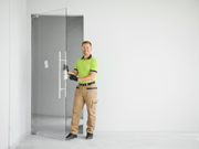 Glass installer fitting a frameless glass door using patch fittings in a clean commercial interior