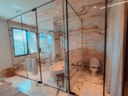 CASMA hydraulic hinges on luxury bathroom frameless glass door with black frame showing premium residential installation with marble walls